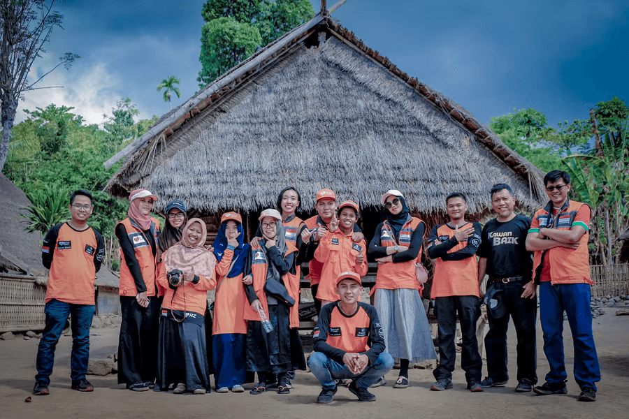 A group of nonprofit volunteers stand in front of a small building.