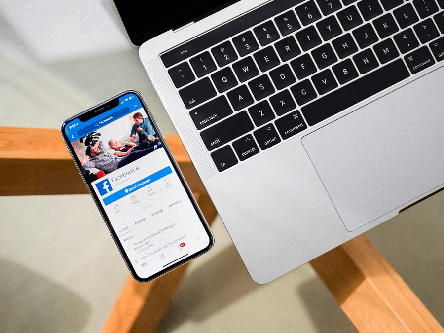 A laptop is open on a table with a phone opened to a nonprofit Facebook page next to it.