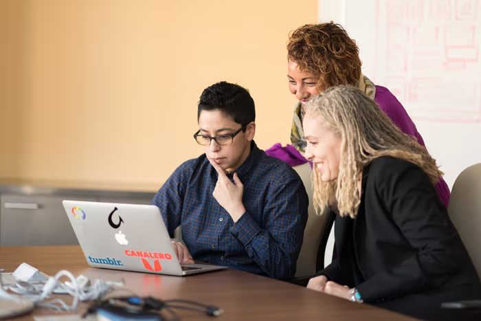 Three people gather together at a laptop to analyze data from their nonprofit tech tool.
