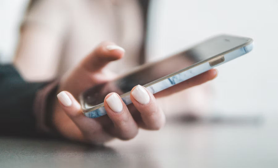 A woman holds a cell phone as she gets ready to text a donation.