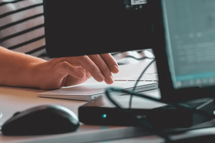 A person’s hands reach out to type on a computer keyboard.