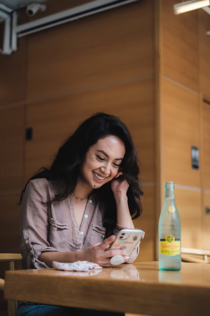 A young woman uses a mobile app at a table.