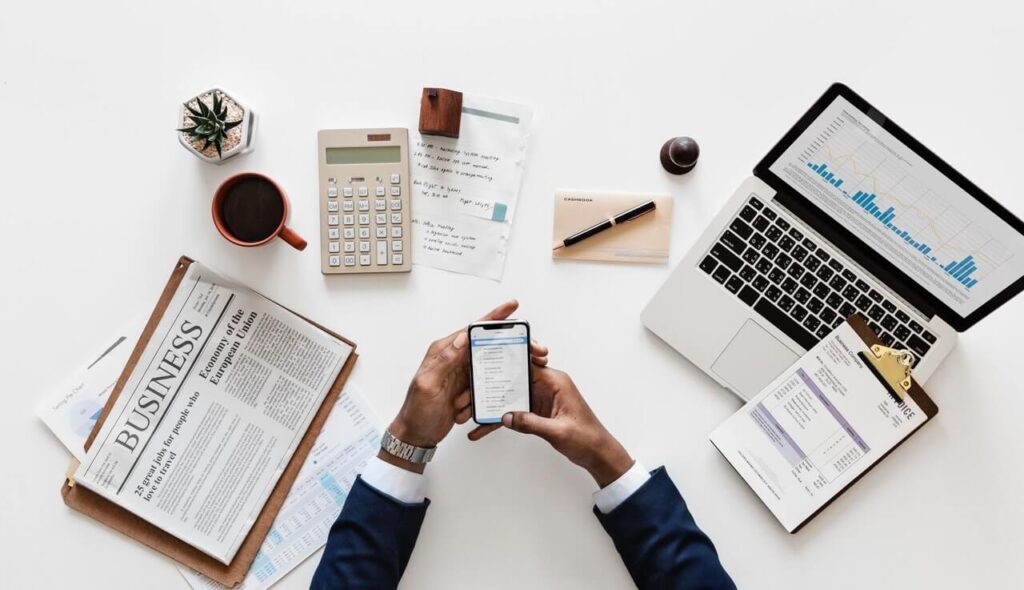 A man has his computer open to his nonprofit website analytics with his phone opened to his nonprofit email marketing platform