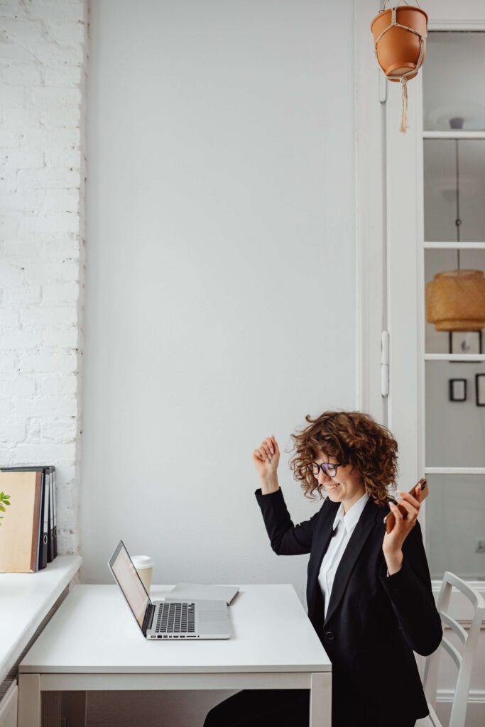 A woman raises her hands in excitement after helping her nonprofit organization