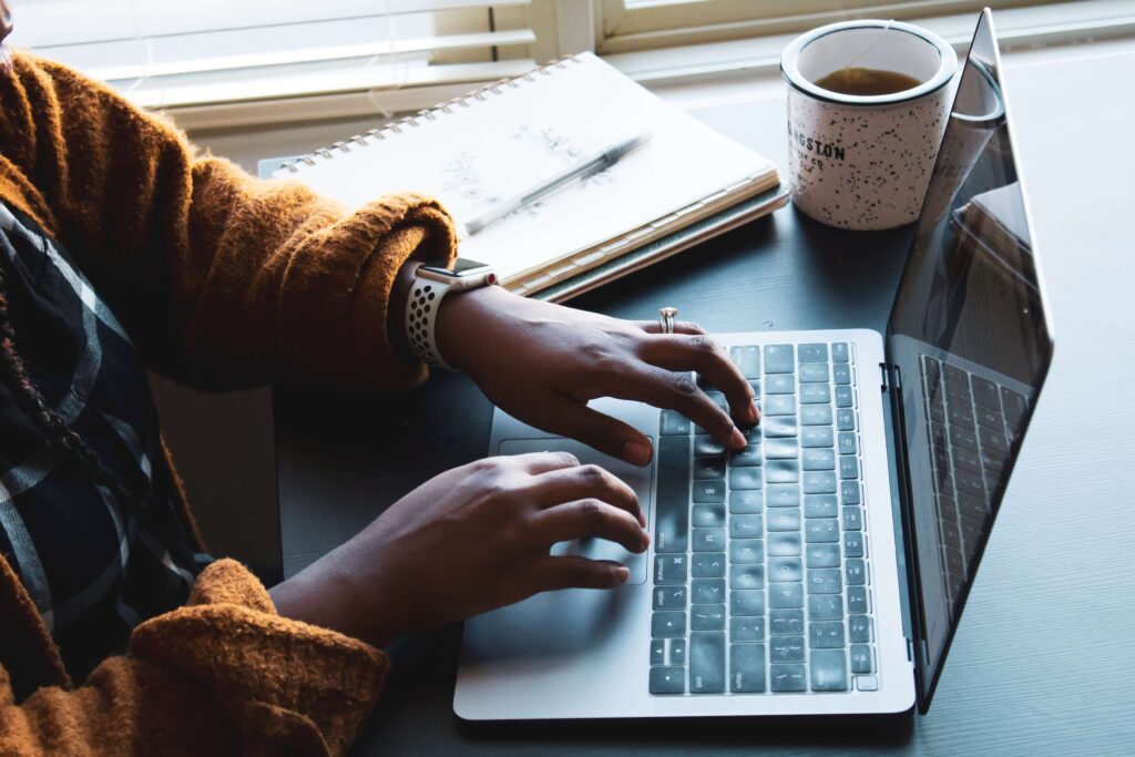 A woman uses her laptop to create blog content using some of the best tools to help with blogging for nonprofits.