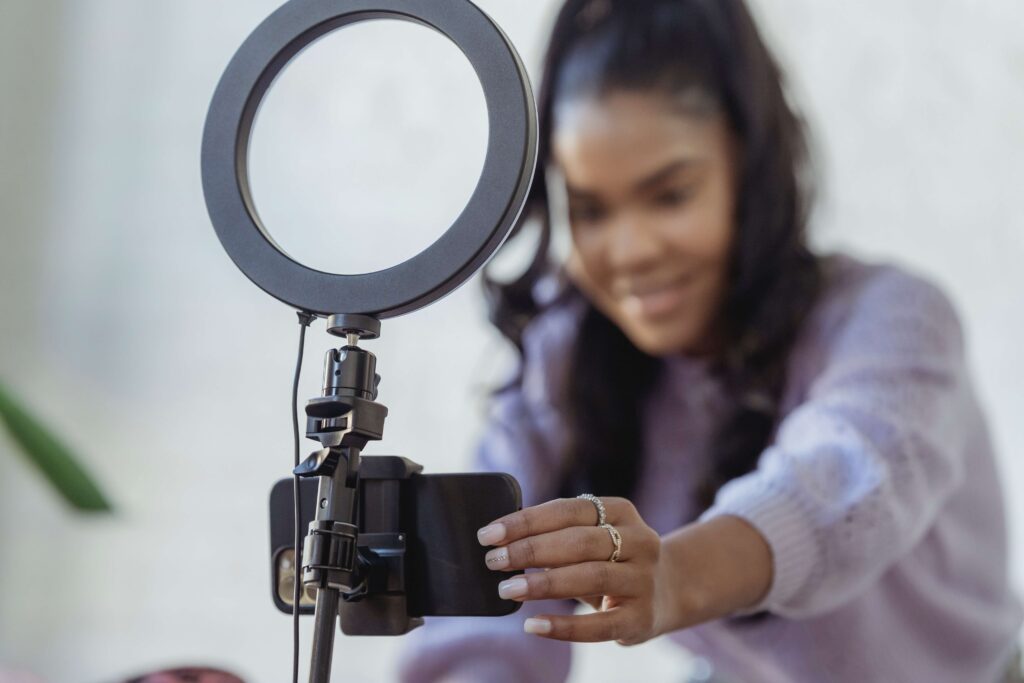 A young woman uses a ring light and a smartphone to take videos for video marketing for nonprofits. 