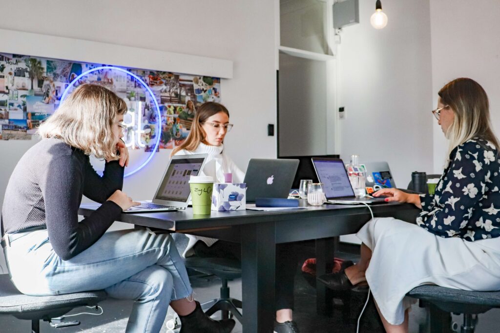 Three professionals sit together on their laptops to map out their digital marketing strategy for nonprofits. 