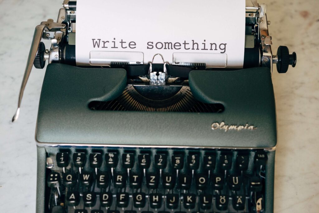 Typewriter has paper in it with the words "write something." 