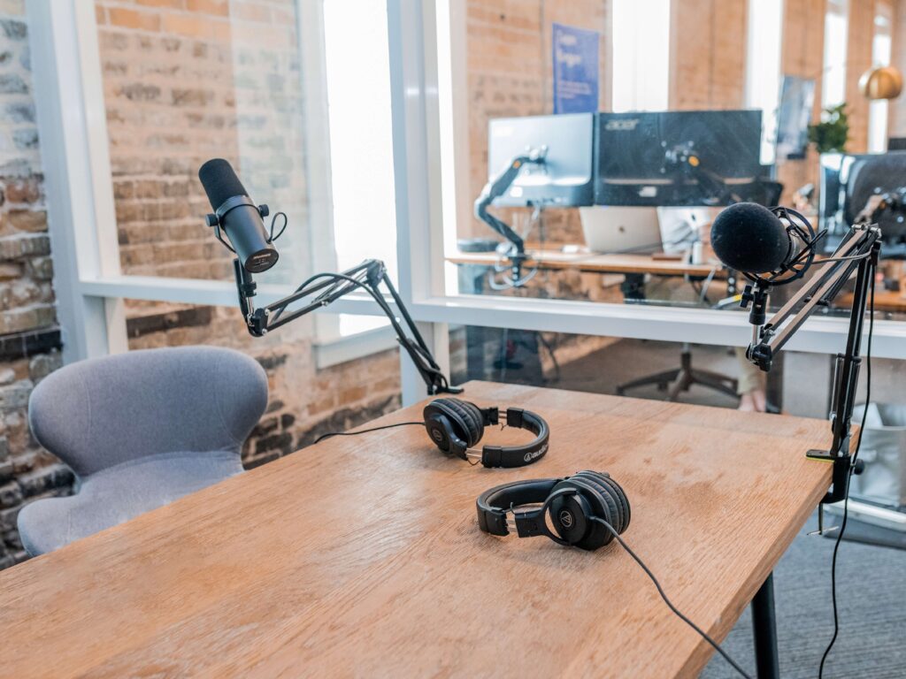 Nonprofit podcast equipment, like headphones, computers, and microphones, rest on a desk. 