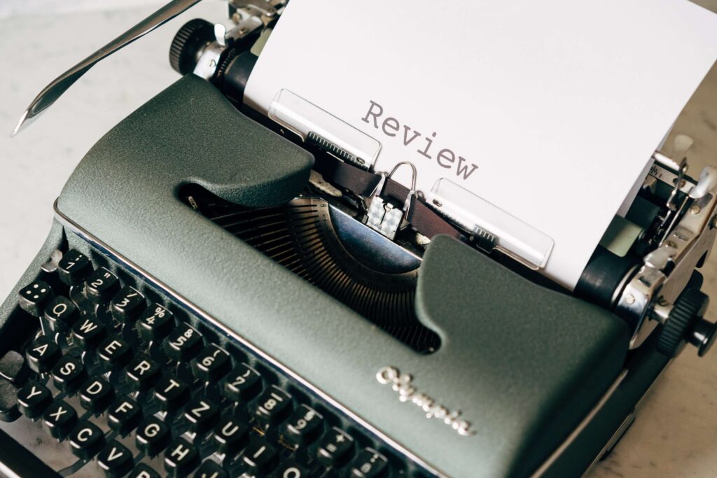 A typewriter types word "review" on paper. 