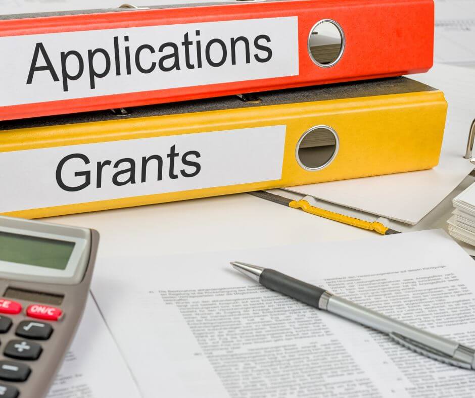 Binders for nonprofit grant applications on a desk